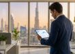 Un homme d'affaires en costume utilisant une tablette avec des graphiques devant la vue panoramique de Dubaï.