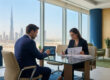 Un homme et une femme d'affaires examinant des documents financiers dans un bureau avec vue sur Dubaï.
