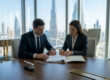 Un homme et une femme d'affaires signant un contrat de liquidation dans un bureau avec vue sur Dubaï.
