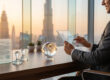 Homme d'affaires travaillant sur une tablette à Dubaï avec un globe terrestre et des documents officiels sur son bureau.
