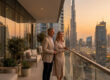 Un couple de retraités élégants sur le balcon d'un appartement de luxe à Dubaï, admirant la vue sur le Burj Khalifa.