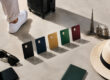 Cinq cartes bancaires colorées alignées au sol avec des accessoires de voyage et des miniatures de monuments de Dubaï.