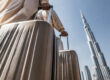 Personnes portant des valises avec la Burj Khalifa en arrière-plan à Dubaï.