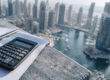 Une calculatrice et un stylo sur une feuille de papier face à la skyline de Dubaï.