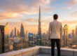 Un homme d'affaires regarde la skyline de Dubaï au coucher du soleil.